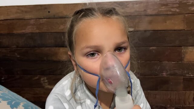 Tired young girl breathes nebulized medication mist for lung disease