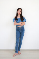 Portrait of young Asian girl in stylish denim outfit standing confidently and looking at camera...