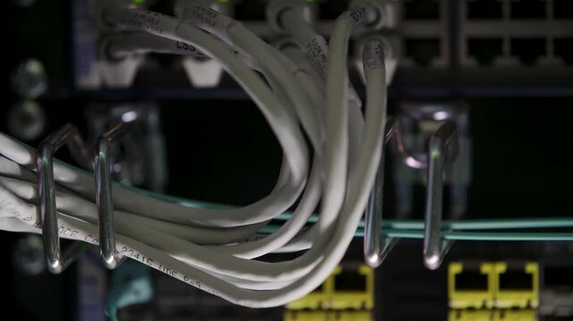 Network Cables Bundled in Metal Hooks Inside Server Rack at Data Center Closeup