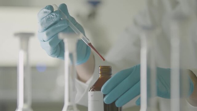 Scientist Using Pipette to Transfer Liquid Into Bottle in Laboratory Setting