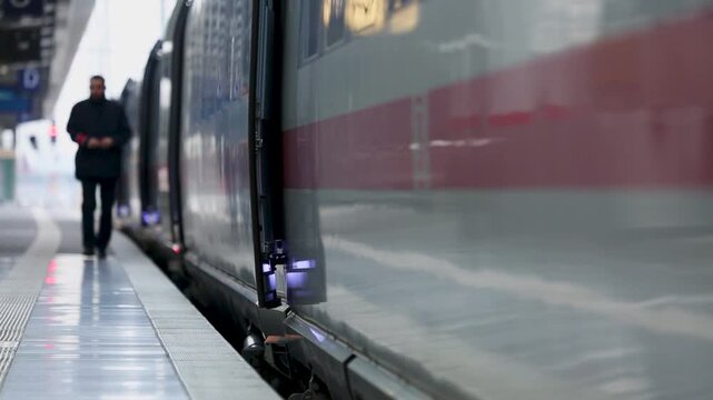 Man Standing on Train Platform Beside Stopped Train at Modern Station During Day