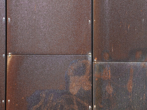 Wall of weathered Corten steel panels in a grid pattern, architectural cladding detail
