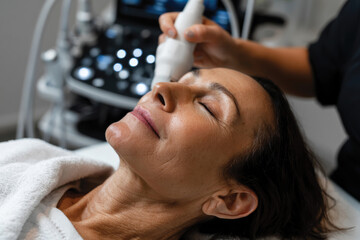 Naklejka premium An elegant setting with a woman enjoying an innovative facial treatment, emphasizing relaxation and the advanced techniques employed in modern skincare practices at a spa.