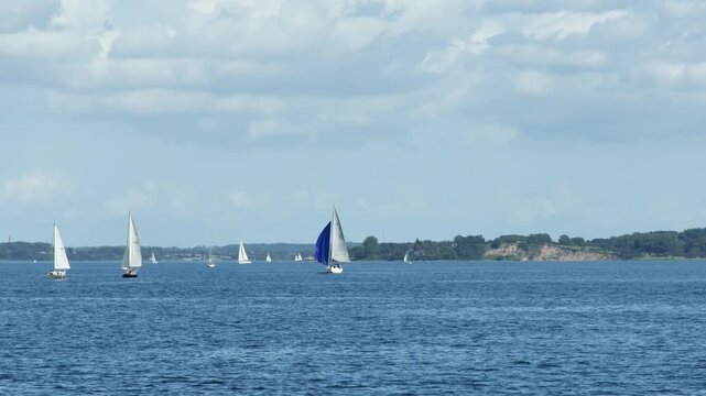 Panoramic view of a busy maritime waterway with sailboats and kayaks moving quickly in an accelerated time-lapse sequence.
