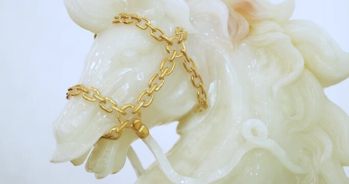 White jade horse sculpture with gold chain on clean background. Luxury and auspicious symbol representing wealth, prosperity and premium lifestyle concept