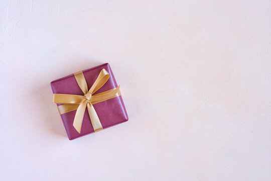 Gift box with ribbon and bow on pink background . Top view