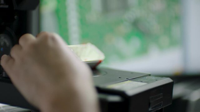 Technician Adjusts Microscope While Inspecting Circuit Board in Laboratory Setting