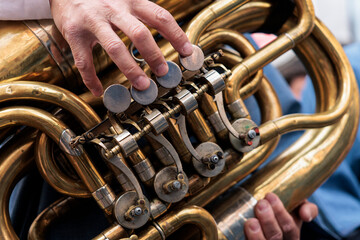 Fototapeta premium Primer plano de manos tocando los pistones de una tuba de metal, Alcoy, España