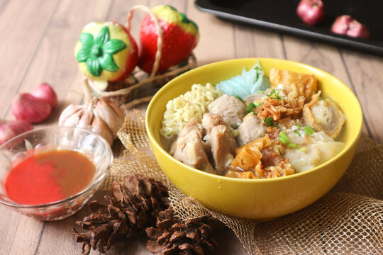 A bowl of bakso, an Indonesian dish from Malang. It consists of chewy meatballs, fried dumplings, wontons, curly egg noodles, and glass noodles, served in clear broth, with sambal and tomato ketchup.