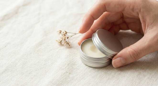 Quiet luxury daily routine balm tin minimalist skincare linen fabric with hand opening container for gentle self care and calm spa hygiene ritual