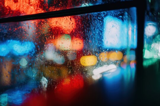 夜になると雨粒が車の窓から街の明かりを曇らせる