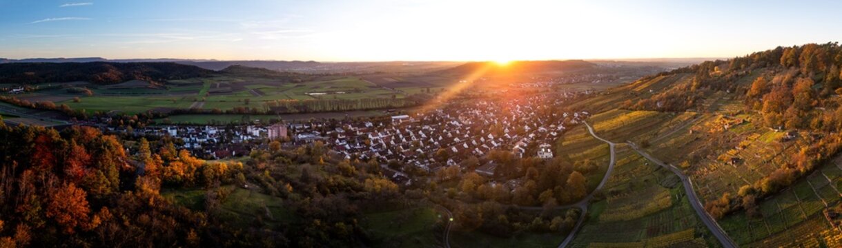 Aerial view of the village of Unterjesingen surrounded by colorful autumn vineyards and forests during a golden sunset Tubingen, Baden-Wurttemberg, Germany.