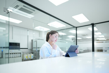 Quality control analyst auditing electronic data integrity via digital tablet. R&D scientist...