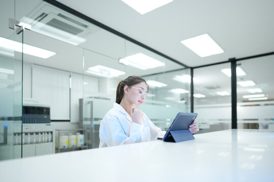 Quality control analyst auditing electronic data integrity via digital tablet. R&D scientist verifying pharmaceutical compliance standards in modern lab.