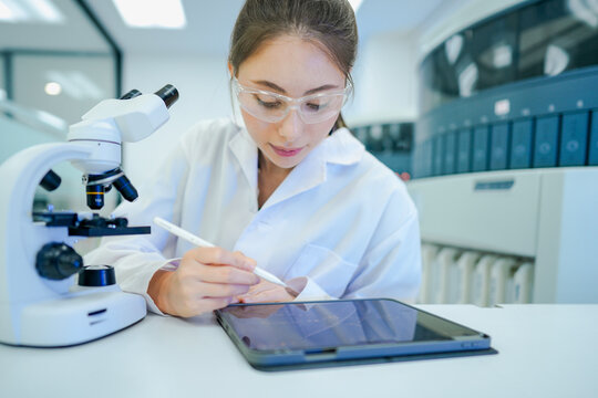 Clinical laboratory scientist recording experimental data into electronic lab notebook (ELN). Biobank manager tracking specimen inventory workflow via wireless LIMS tablet.