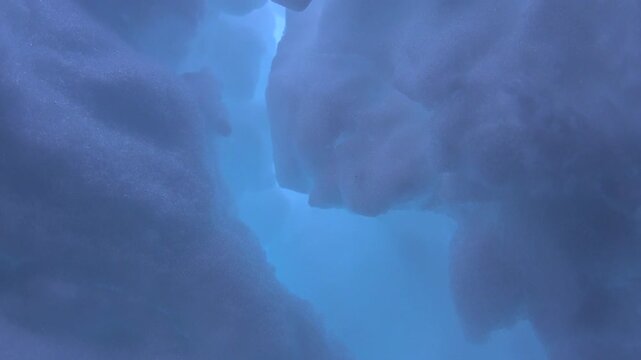 Frozen ice crack and crevice inside light blue ice cave across winter geology wilderness. Interior view of a cavity hole with intricate patterns translucent glacial formations.