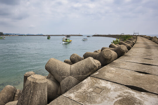 Dramatic storm clouds over manmade wave breaker with fishing boats in Marang Terengganu