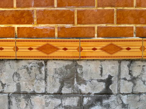 Weathered stone bricks wainscoting with decorative diamond tiles belt and orange red brick wall at the top. Decorative wall finishes. Seamless background texture.