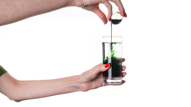 Liquid Chlorophyll in a Glass of Water in hand, Superfood, Healthy Eating, Detox and Diet Concept