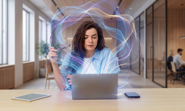 Creative woman working on laptop surrounded by abstract digital light interface