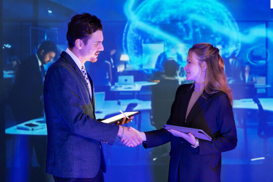 Business professionals shake hands during a conference with a global map in the background highlighting international connections