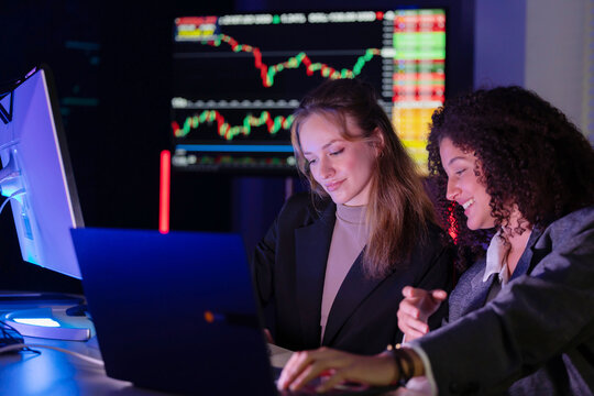 Colleagues discuss stock market trends in a modern office setting during evening hours