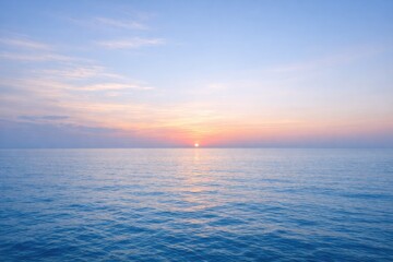 Obraz premium Serene ocean horizon at sunrise with soft pastel colors in the sky and calm blue water reflecting the morning light over the sea