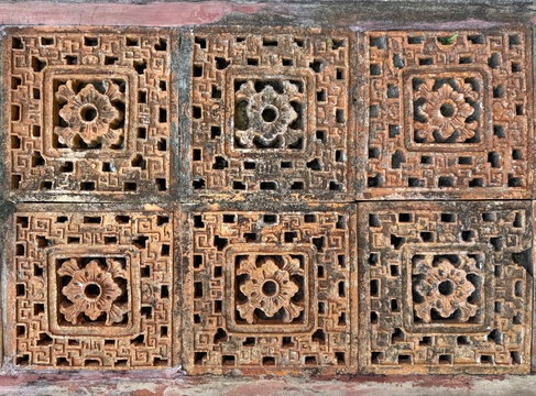 Close up pattern of molded clay or ceramic latticework, or Roster, in ethnic traditional floral pattern. Finished in brown terracotta color. Weathered and rustic, found in heritage or colonial buildin