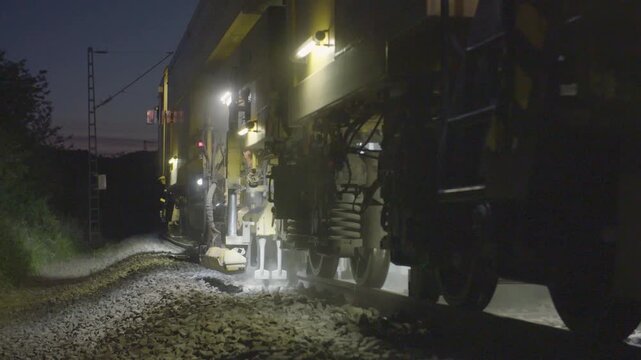 Maintenance Train with Illuminated Worklights Operating on Railway Tracks at Night