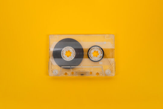 Transparent vintage audio cassette tape isolated on a vibrant yellow back