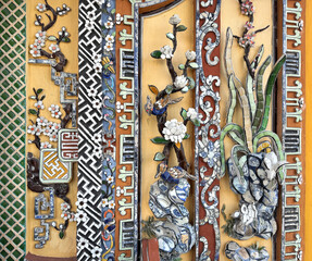 Fototapeta premium Beautiful fully carved wall with ornate floral sculpture, petals, and swirls engraving. Combining French baroque and oriental asian style. In vibrant red, yellow, blue, and green. 3d relief wall.