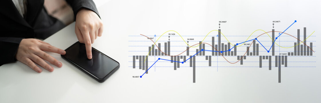 A businessman interacts with a smartphone displaying financial data while analyzing stock market trends on a nearby screen, showcasing modern business technology and analysis. Ledger