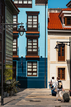 Tourists walking with luggage in colorful street in Luanco Spain