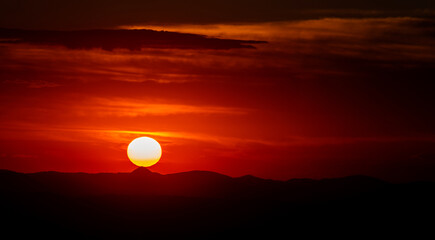 Fototapeta premium Dramatic Mountain Sunset with Clouds and Visible Sun Disk