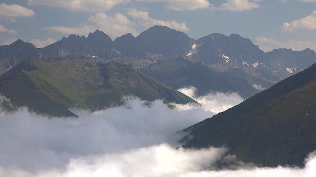 Sea of clouds and fog covering valleys between high altitude mountain peaks in landscape. Natural phenomenon with thick cloud layer blanketing mountainous terrain creating view.