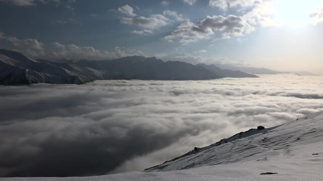 Sea of clouds blankets alpine snowy mountains during winter sunrise panorama in the Pyrenees. Cloud ocean highlights high altitude, fog blanket, and valley fog plus cantabrian range.