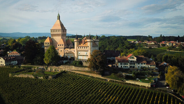 Aerial view of the medieval Vufflens-le-Chateau castle with its prominent central tower and surrounding vineyards in Vufflens-le-Chateau, Vaud, Switzerland.