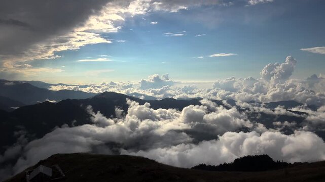 Sea of clouds and fog covering valleys between high altitude mountain peaks in landscape. Natural phenomenon with thick cloud layer blanketing mountainous terrain creating view.