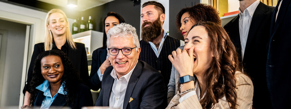 Multicultural business team laughing together during informal office meeting in modern workplace. Millennials, generation x and gen z colleagues sharing positive moment and strong teamwork culture.