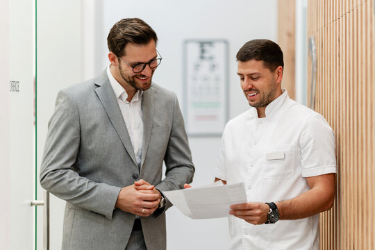 handsome middle-aged businessman patient, talking with the doctor in the corridor of the ophthalmology clinic