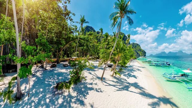360 view of White sand beach at Entalula, El Nido, Palawan with swaying palms, turquoise water, traditional bangka boats and dramatic limestone karsts beneath a blue sky with clouds in Philippines,