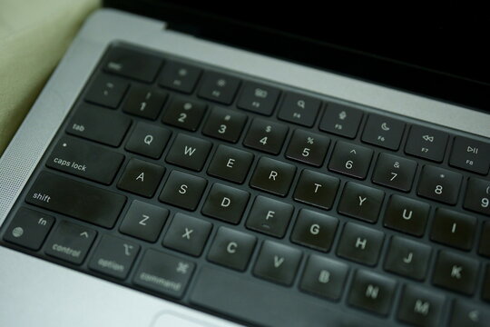 Close-up of a modern laptop keyboard with black QWERTY keys on a silver metallic chassis. High angle view showing detailed buttons for business, technology, and work from home concepts.