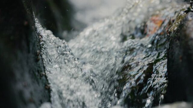 Clear mountain stream with pure water flowing and bubbling over natural rocks in a pristine wilderness environment, dynamic motion of fresh transparent water in a rocky creek, natural landscape 