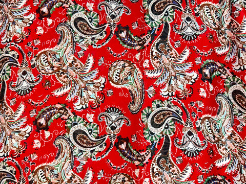 Close up of red fabric with random paisley pattern. Abstract flower, leaves, foliage, and swirls paisley shape. For fabric, wallpaper, graphic background. Seamless background texture.