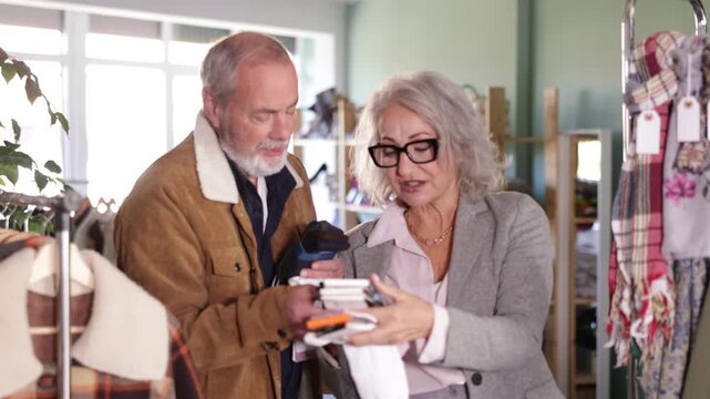 Elderly man and a woman together choose a set of socks for every day. Pensioners in a clothing store pick up accessories. High quality 4k footage