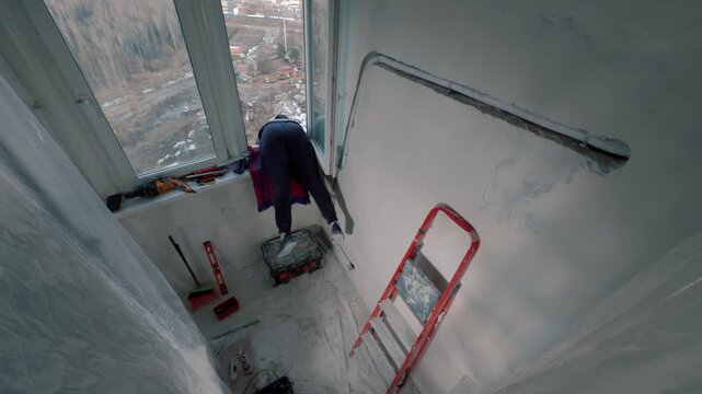 Woman repairing wall near window with ladder