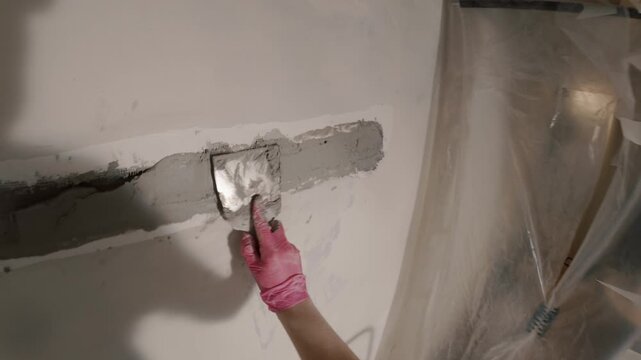 Spreading plaster on wall crack with trowel