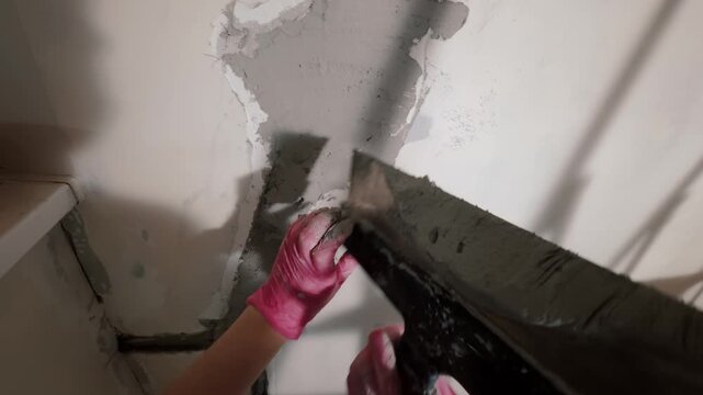 Applying plaster with trowel on wall corner during repair