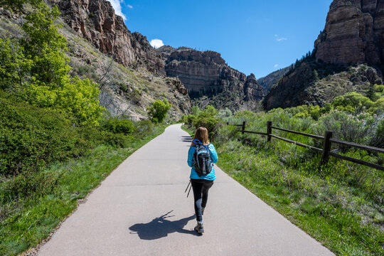 Woman hiking on Hanging Lake Trail in White River National Forest in Glenwood Canyon, Colorado on clear sunny spring day.