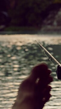 Vertical video. Close View of Fishing Rods with Blurred Foot in Foreground Facing Calm Lake with Fountain Waiting for Bite Relaxing Outdoor Leisure Scene Nature and Recreation
